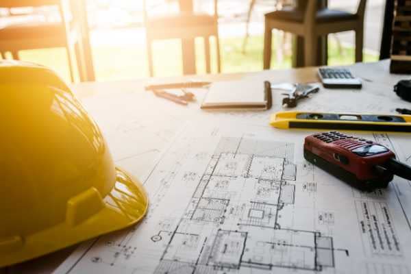 hard hat and architectural plans on construction site